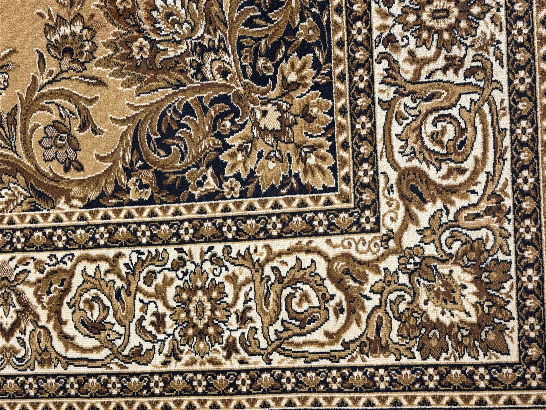 Persian design golden beige ground rug, the field with symmetrical scrolling foliate and floral designs, central floral medallion, bordered by a multi-layered band with floral and vine patterns in contrasting beige and dark brown tones