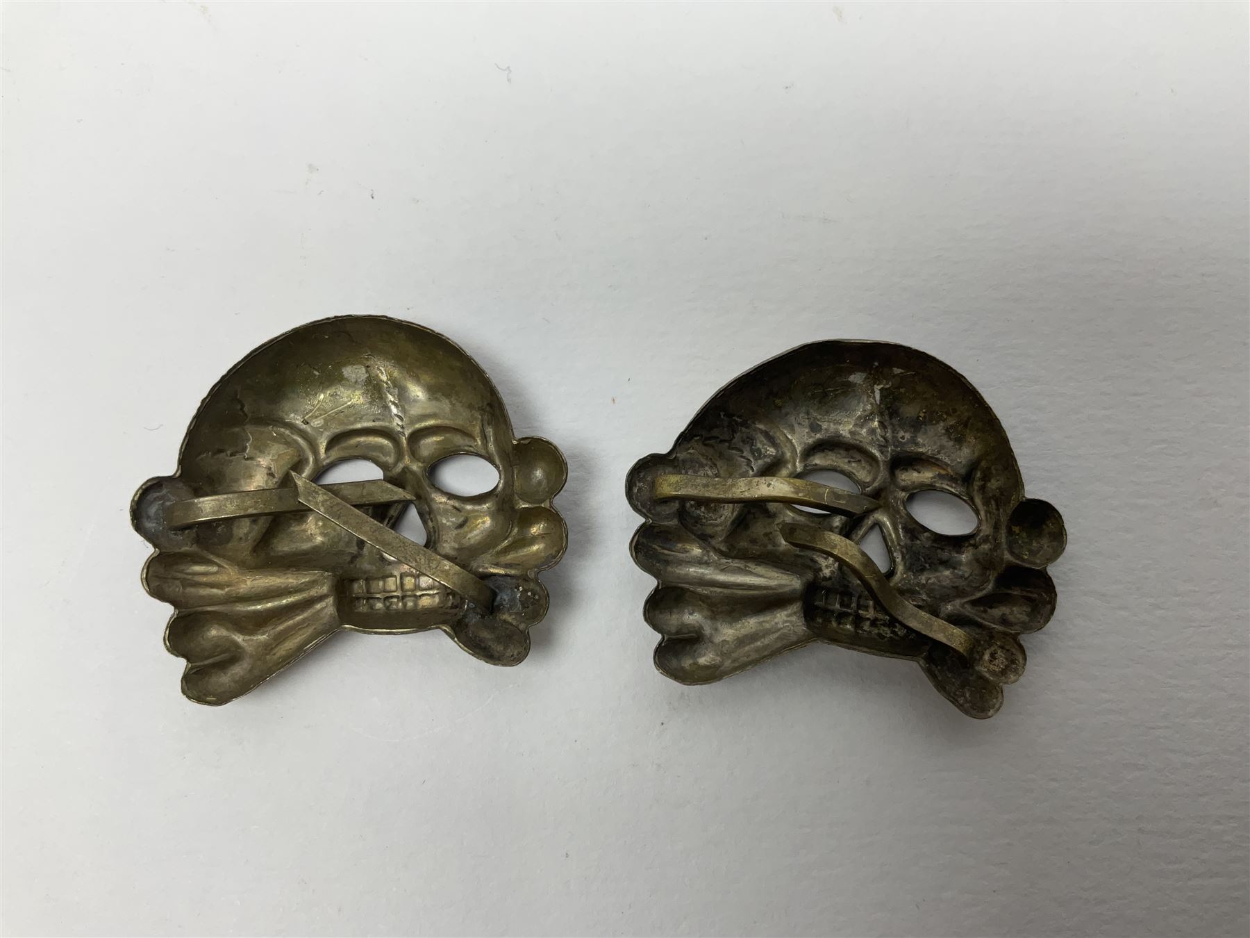 Five German 'SS' visor cap metal badges comprising one eagle and four skull and cross-bones (5)