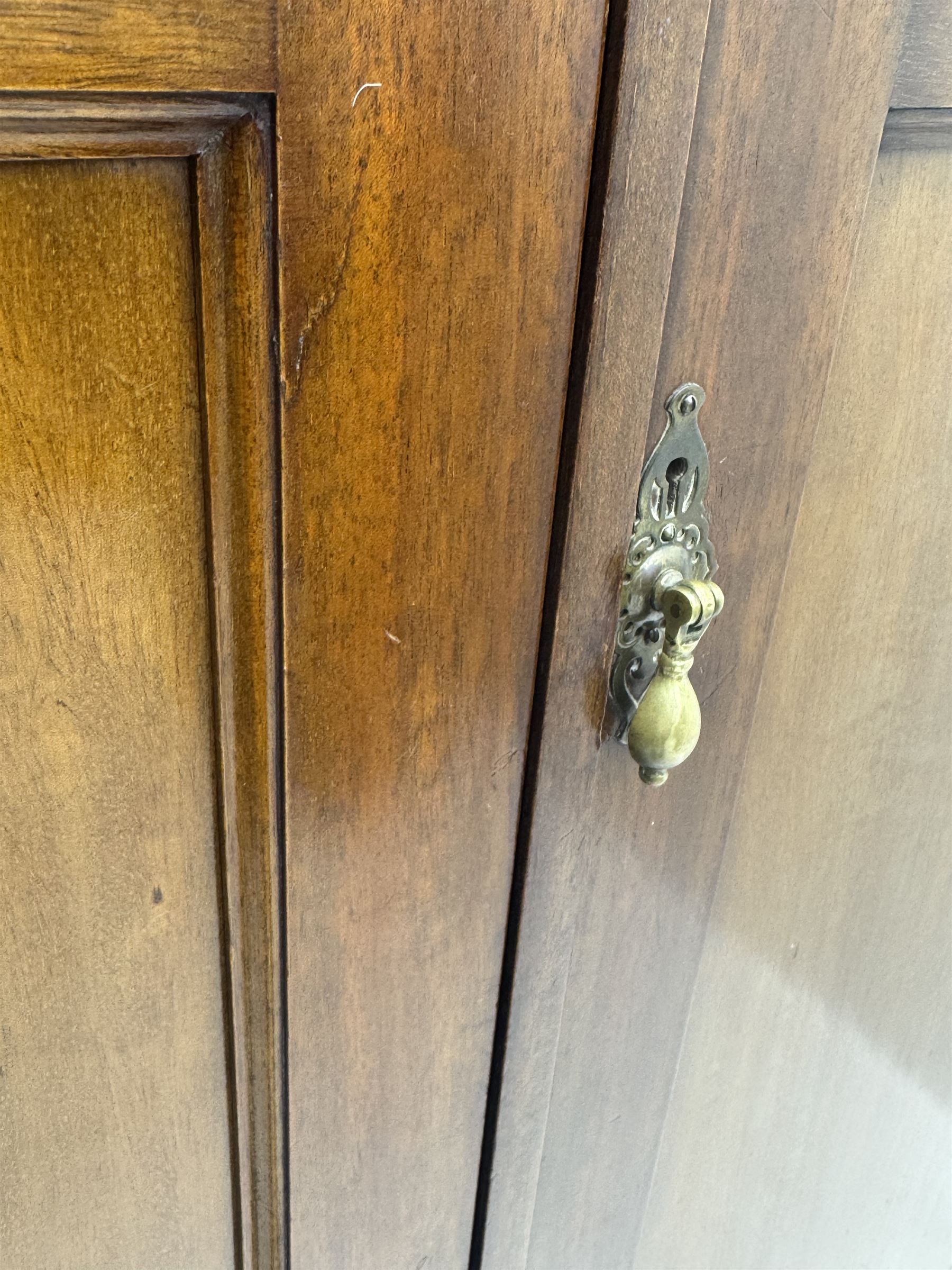 Wylie & Lochhead, Glasgow - early 20th century mahogany and satinwood double wardrobe, projecting cornice over panelled doors, interior fitted with mirrored door, shelves, drawers, hooks and hanging rail, raised on bracket supports with ceramic castors