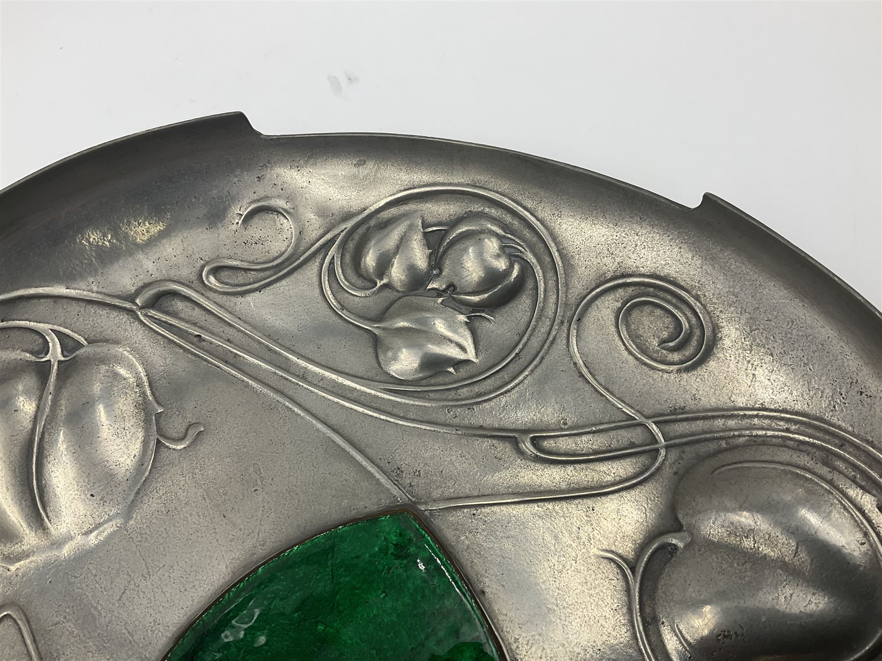Liberty & Co Tudric pewter Bollelin tray, designed by Archibald Knox, of circular form with shaped edge, cast in relief with foliate tendrils surrounding a green enamel cartouche, impressed beneath Made by Library & Co English Pewter 044, D25.5cm