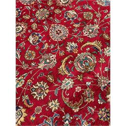 Persian Tabriz crimson ground carpet, decorated with swirling leafy branches and large palmette motifs, the pale ground border decorated with trailing foliate pattern, within floral guard stripes