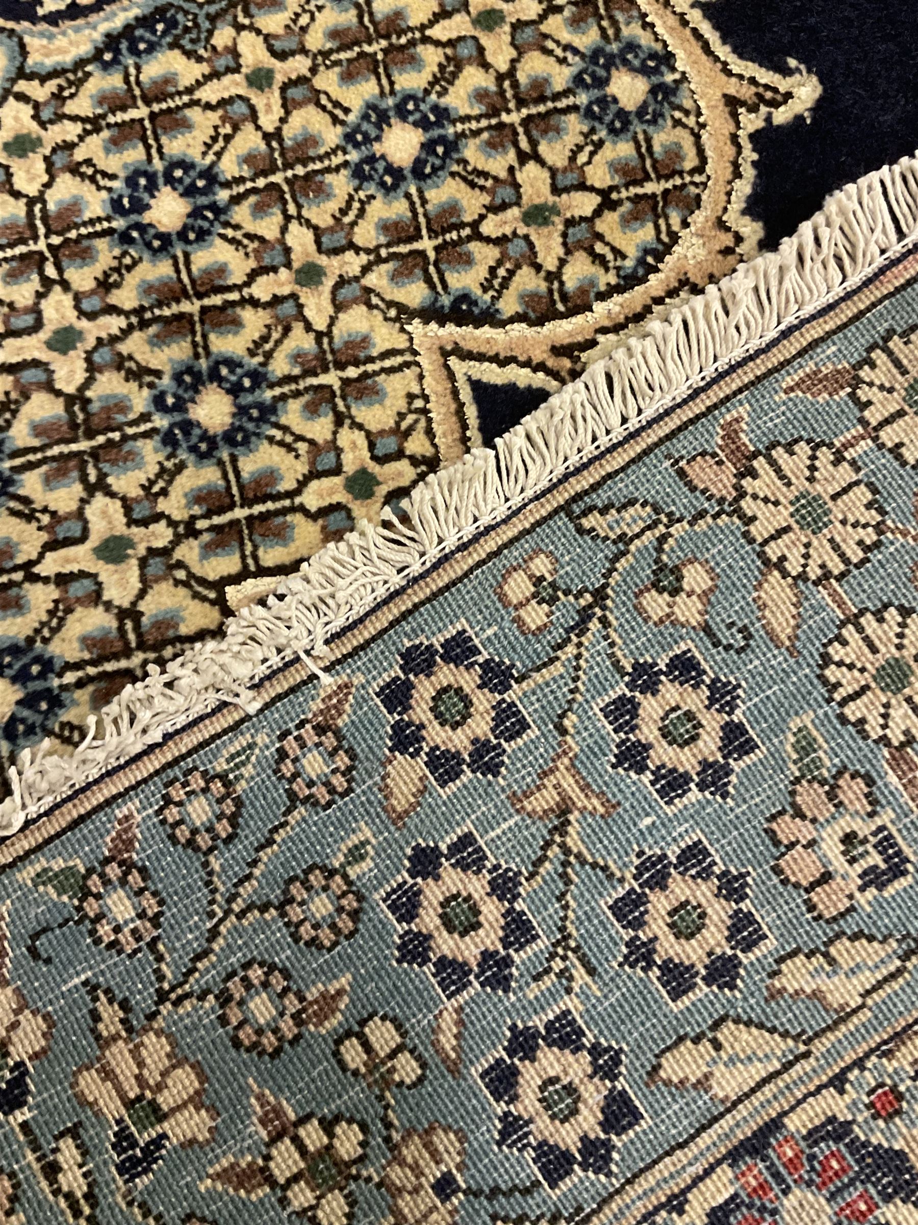 Central Persian Qum indigo ground rug with silk inlay, the plain field decorated with floral design medallion and lattice spandrels, the wide border decorated with trailing flowers and foliage 