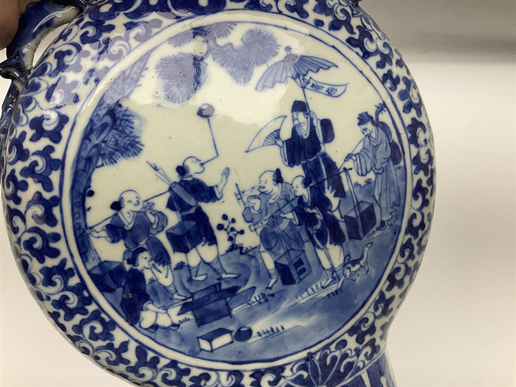 19th century Chinese blue and white moon flask vase, the central panel depicting musicians, bordered by floral, foliate and scroll decoration, with lizard handles to each shoulder, upon an oval foot, H31cm 
