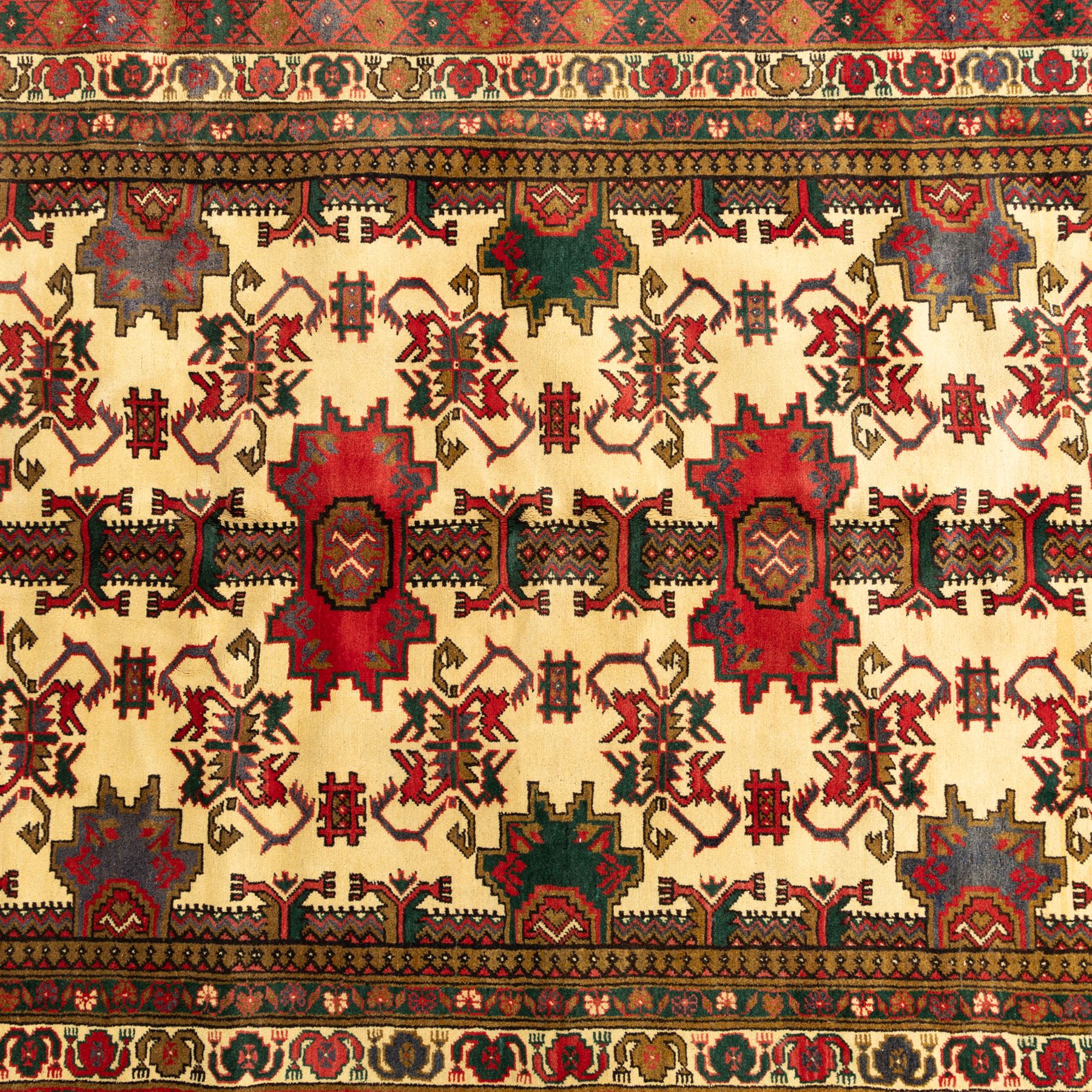North East Persian Gochan hand-knotted rug, ivory field decorated with a vertical column of stepped polygonal medallions flanked by stylized geometric floral motifs enclosed by multiple borders incorporating rosette and reciprocal devices, in a palette of madder red, indigo, olive green, and aubergine, with cotton fringe ends  
