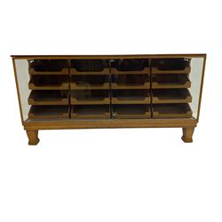 Early 20th century oak framed haberdashery shop counter, veneered top with glazed front and sides, fitted with sixteen graduating drawers with oak fronts and handles, raised on shaped supports