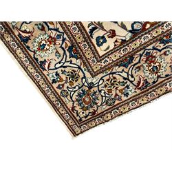 Persian Kashan ivory ground carpet, the field decorated with scrolling branches with foliate and palmette motifs, repeating border with stylised plant motifs, within floral and geometric pattern guard stripes 