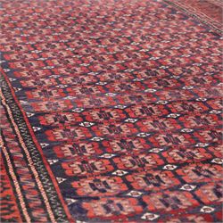 North East Persian Turkoman hand-knotted rug, indigo field densely decorated with an all-over repeating design of geometric gul motifs in shades of madder red, aubergine, and dark brown, highlighted with small ivory details, framed by multiple narrow guard borders and a main border with angular geometric motifs flanked by zig-zag borders, with cotton fringe ends 