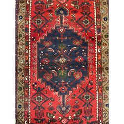 Persian Hamadan rug, red ground field decorated with pole medallion and stylised flower head motifs, the border decorated with Boteh and floral motifs