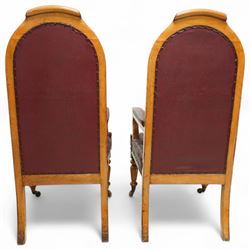 Impressive pair of mid-Victorian oak throne or hall chairs, arched backs on fluted supports with a deep buttoned upholstered panel and upholstered curved arms over fluted seat rails and tapering turned front legs with original brass and brown porcelain castors, and out-swept rear supports