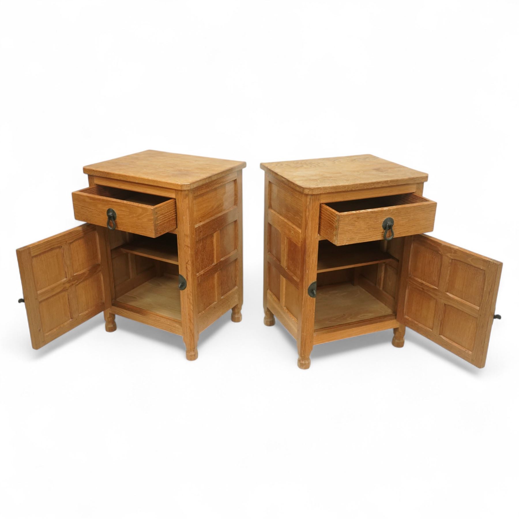 Beaverman - pair of oak bedside cabinets, each with plain rectangular top over single drawer and cupboard below with fielded panels and wrought iron hardware, with signature carved beaver, by the workshop of Colin Almack, Thirsk