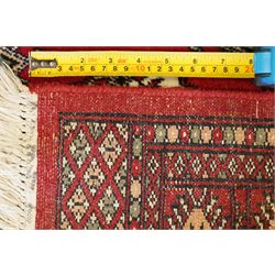 Two Afghan Bokhara crimson ground rugs, the fields decorated with repeating Gul motifs with geometric guard bands (126x190 & 157x250)