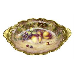 Mid 20th century Royal Worcester dish decorated by John Freeman, of oval form with gilt shaped rim and twin shell handles, hand painted with a still life of fruit upon a mossy ground, signed Freeman, with black printed mark beneath, W30cm