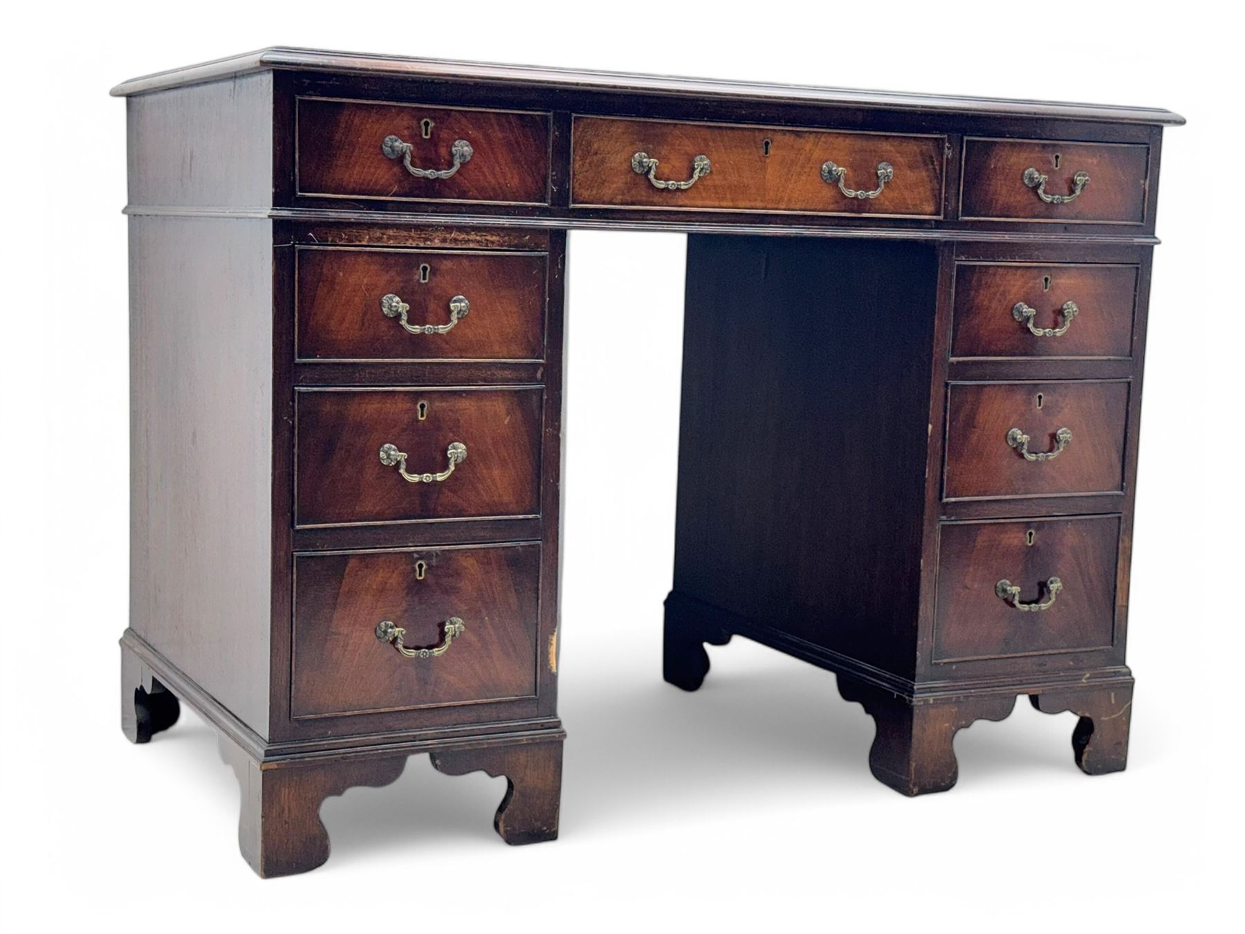 Georgian design mahogany kneehole desk, moulded rectangular top with red gilt-tooled leather writing surface, over an arrangement of nine cock-beaded drawers with brass swan neck handles, on bracket feet