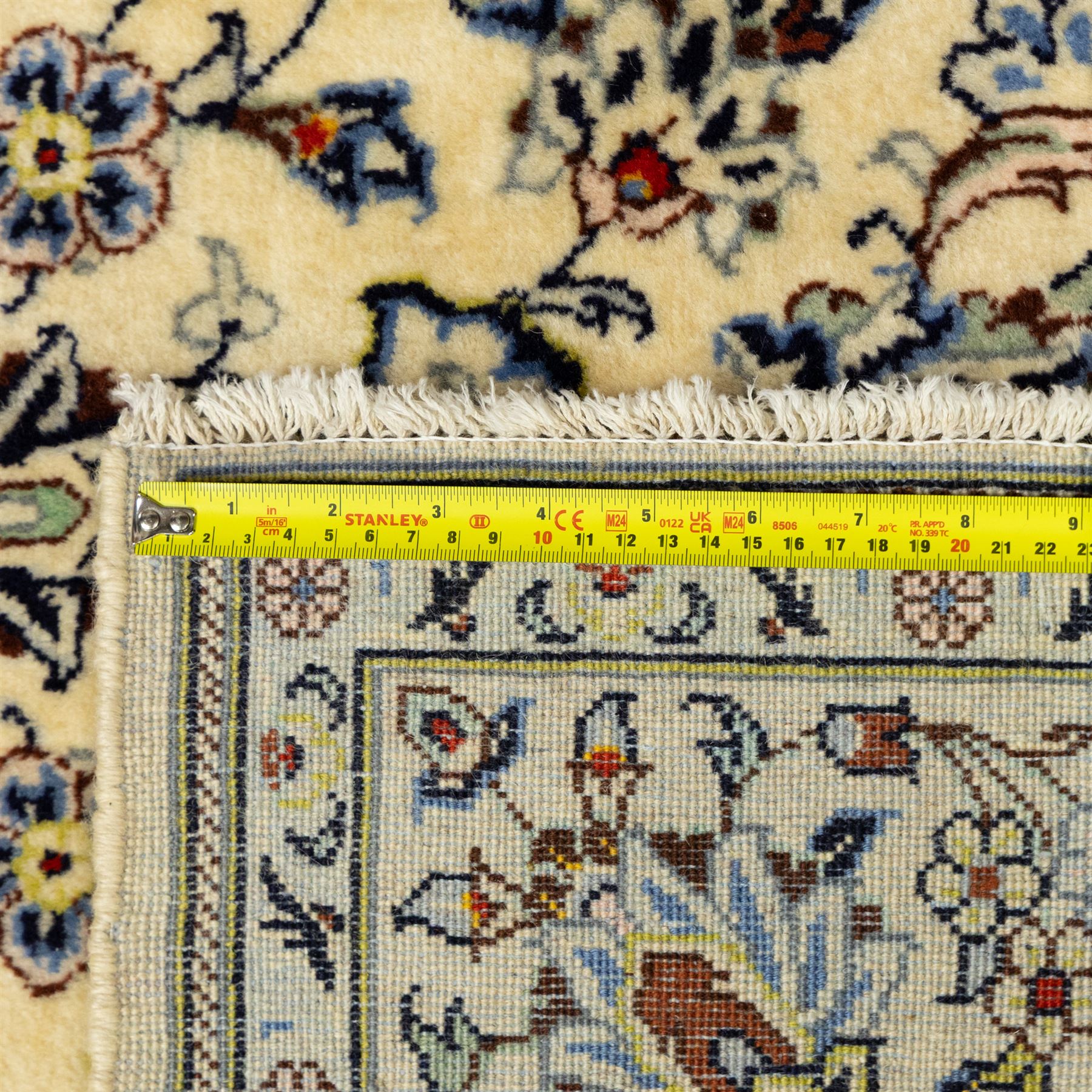 Central Persian Kashan hand-knotted rug, ivory ground, with a small central floral medallion and pendants, the field finely decorated with blue, cream and soft red scrolling vines, flowerheads and palmettes, within an ivory floral border and narrow guard stripes, with cotton fringes