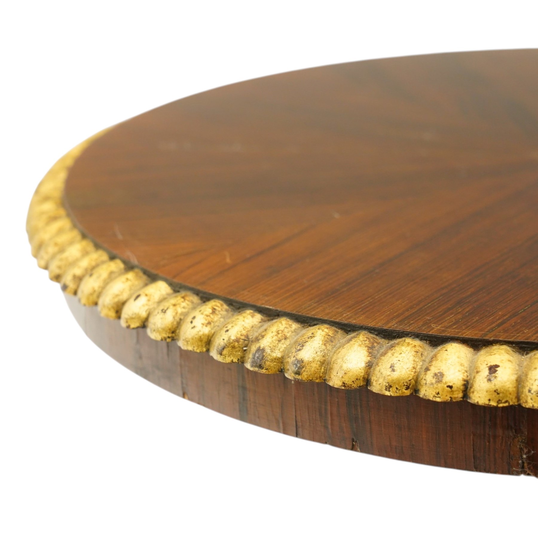 French Empire design rosewood and parcel-gilt occasional table, the circular top with sunburst veneer and giltwood gadrooned edge, raised on a turned and lobed pedestal terminating to a triform platform base with gilt beading, raised on three large paw feet with scrolling foliate brackets