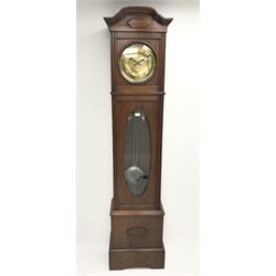 Early 20th century Arts and Crafts oak longcase clock, shaped moulded cornice over circular brass dial with Arabic numerals and beaten central detail, the trunk with circular convex glass and oval bevel glazed aperture, moulded uprights, the weights with brass tops and bottoms and beaten polished metal cases with rivets, the pendulum bob matching, twin weight driven eight day movement striking the hours and half on coil, H211cm