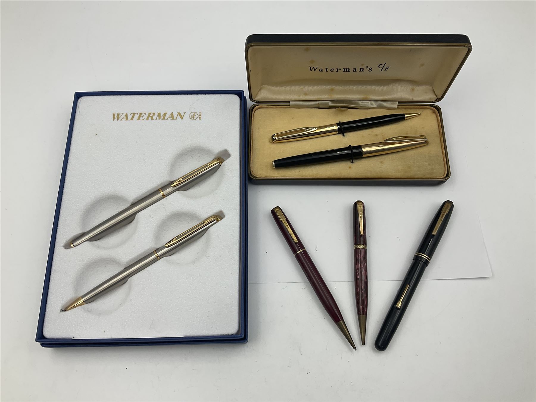 Group of Waterman pens and propelling pencils, to include a fountain pen, the black barrel with rolled gold cap and nib stamped 14ct, together with a matching propelling pencil, in box, together with a further fountain pen with gold nib stamped 14ct, stainless steel fountain pen and rollerball set in box, propelling pencil with maroon barrel etc, largest L13cm (7)
