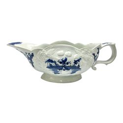 Large 18th century Lowestoft sauce boat, circa 1770, the body decorated with Hughes type floral moulding, and painted in underglaze blue with an Oriental landscape, and foliate sprigs, L23cm