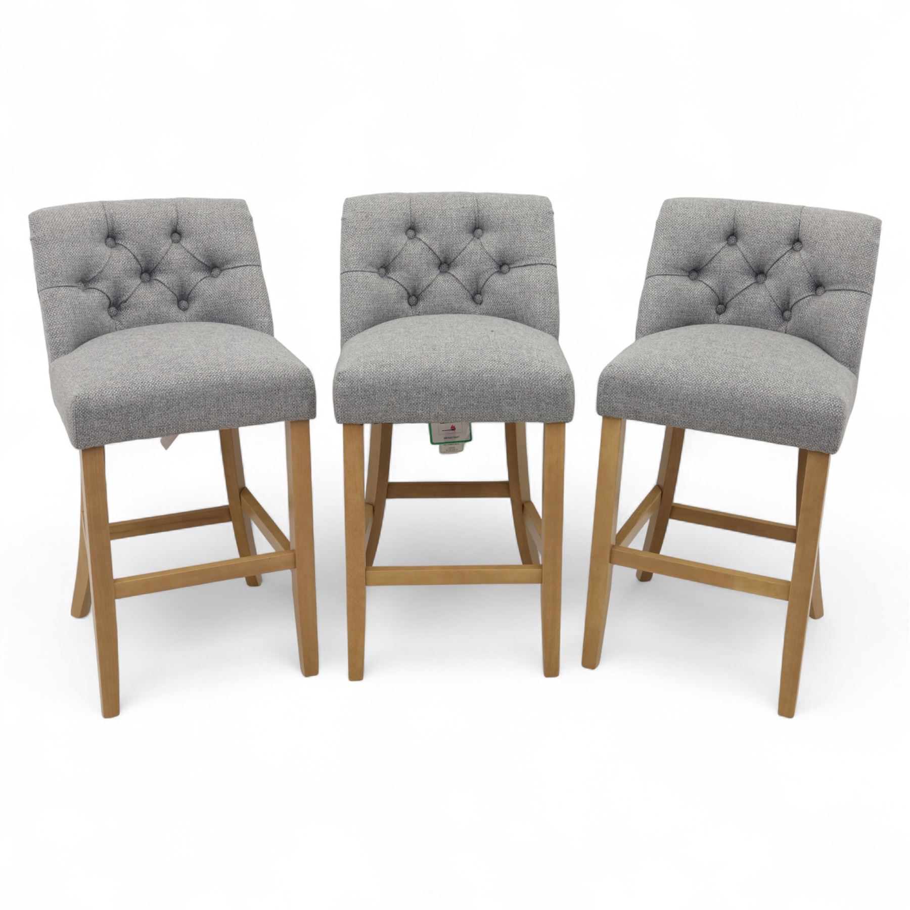 Contemporary set of three upholstered bar stools, each with button-tufted grey fabric backrest and seat, raised on light oak finish square legs united by stretchers