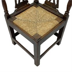 18th century country elm and oak corner chair, the shaped cresting rail terminating to swept arm resets, supported by turned columns and pierced shaped splats, over a drop-in rush seat, raised on square supports united by box stretcher