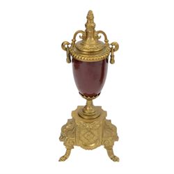 Continental-20th century clock garni in a mid 19th century style case, with porcelain panels and dial, spring driven two train movement with a floating balance escapement, striking the hours and half hours on two bells. With conforming urns. 