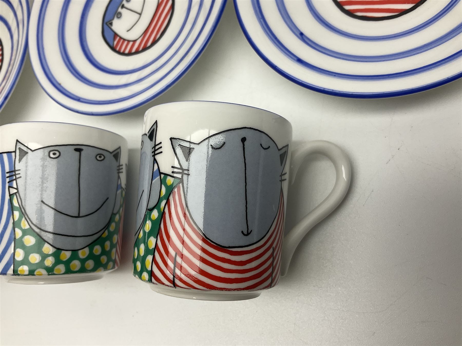 Modern studio pottery by Josie Firmin, to include cup and saucer, three espresso cups and saucers, pair of egg cups etc, each hand painted with varying cartoon cat designs
