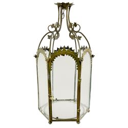 19th century brass and clear glass hexagonal hall lantern, with scrolling wire work open domed top over six arched panels, including a hinged door, the base enclosed with a circular glass panel on turned feet, H64cm