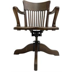 Early 20th century swivel office desk chair, shaped bar back over vertical rails, dished seat, on four splayed supports