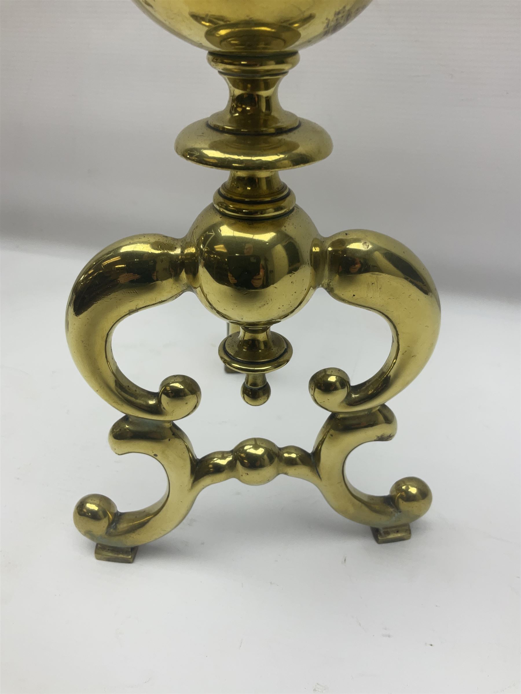 Pair of early 20th century brass fire dogs, each with sphere and urn finial, upon a scrolling base, H38cm