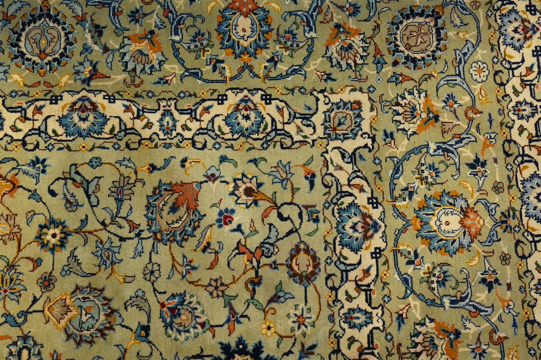 Central Persian Kashan hand-knotted carpet, pale blue field decorated with a finely drawn all-over scrolling floral vine design incorporating stylized palmettes, rosettes and foliate sprays, with a small central circular medallion, enclosed by a conforming floral vine border between multiple guard stripes, with cotton fringe ends  