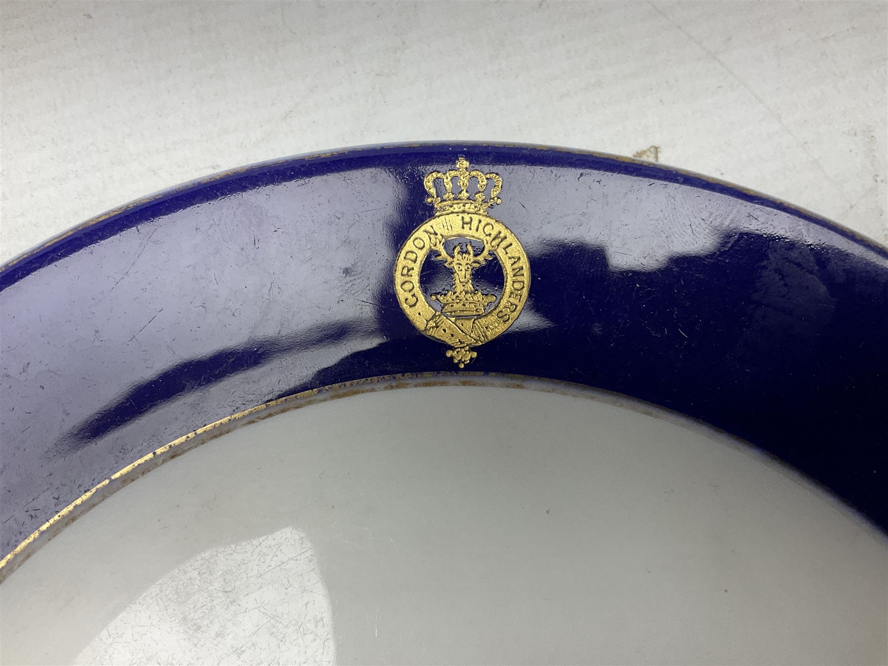 Collection of Regimental dinner wares, Comprising Royal Sussex; two dinner plates, two side plates and a soup bowl, Royal Leicestershire; two dinner plates, East Yorkshire Regiment side plate and Gordon Highlanders side plate, all decorated with the regiment's crests and blue and gilt boarders (9)