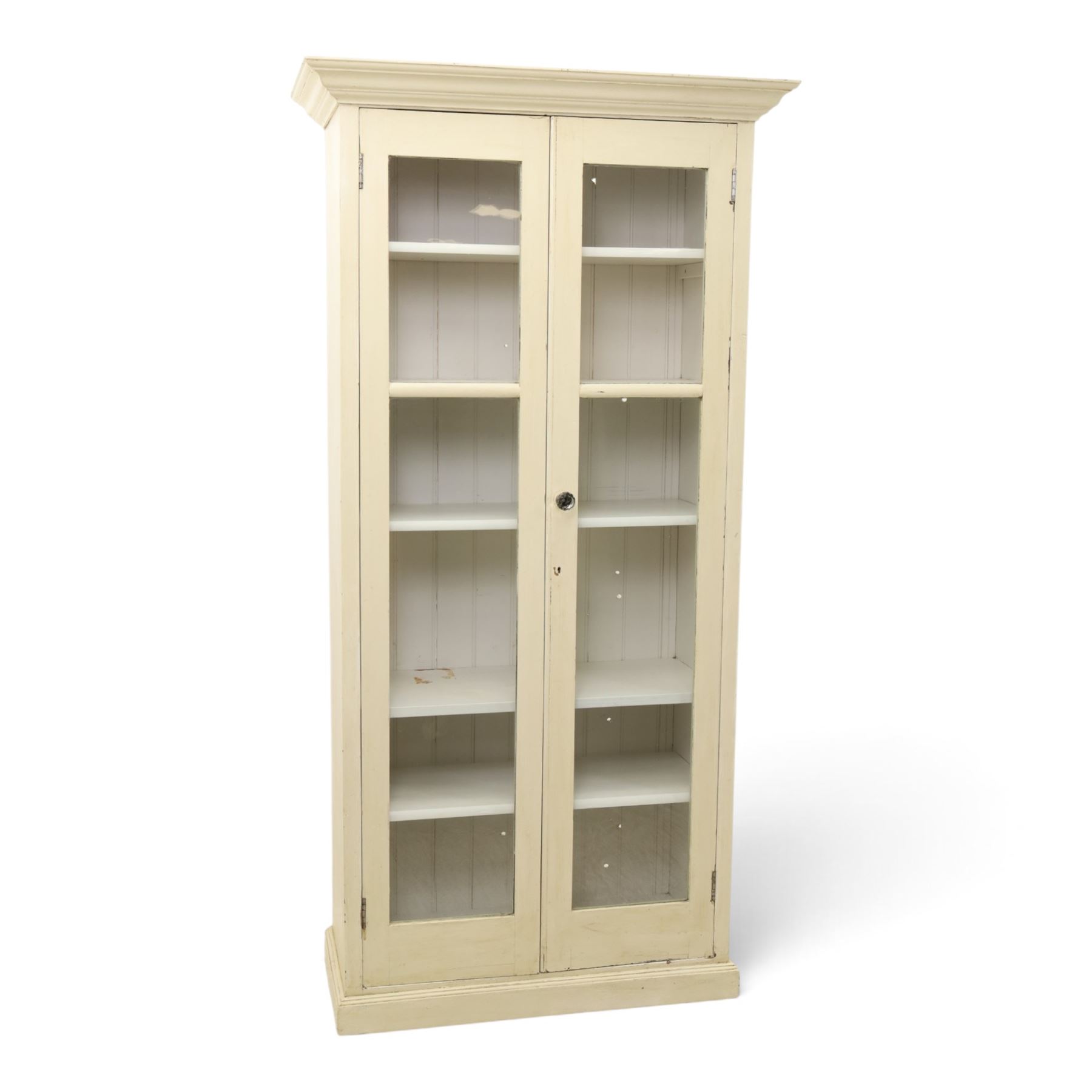 Traditional white painted pine display cabinet, projecting cornice above two glazed doors enclosing five fixed shelves, tongue and groove back raised on a plinth base