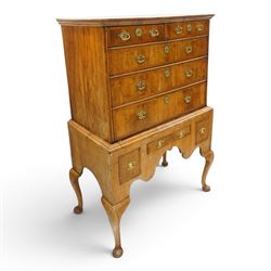 George II figured walnut chest-on-stand, the moulded cavetto top over two short and three long graduating cross-banded drawers, each fitted with pressed brass handle plates, the base fitted with three further drawers over a shaped apron, raised on cabriole supports with pad feet