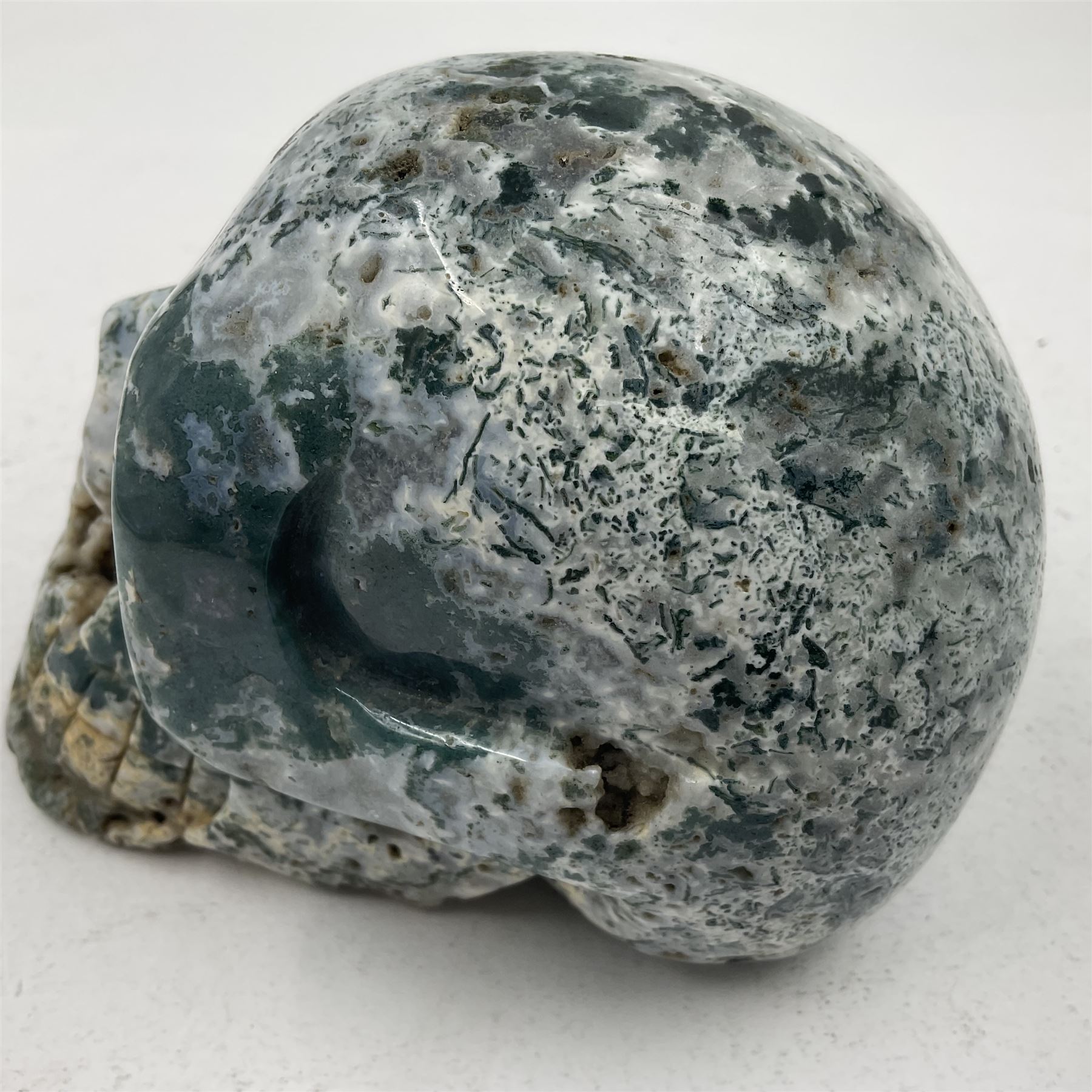 Carving of a skull in moss agate, H9cm, L12cm 