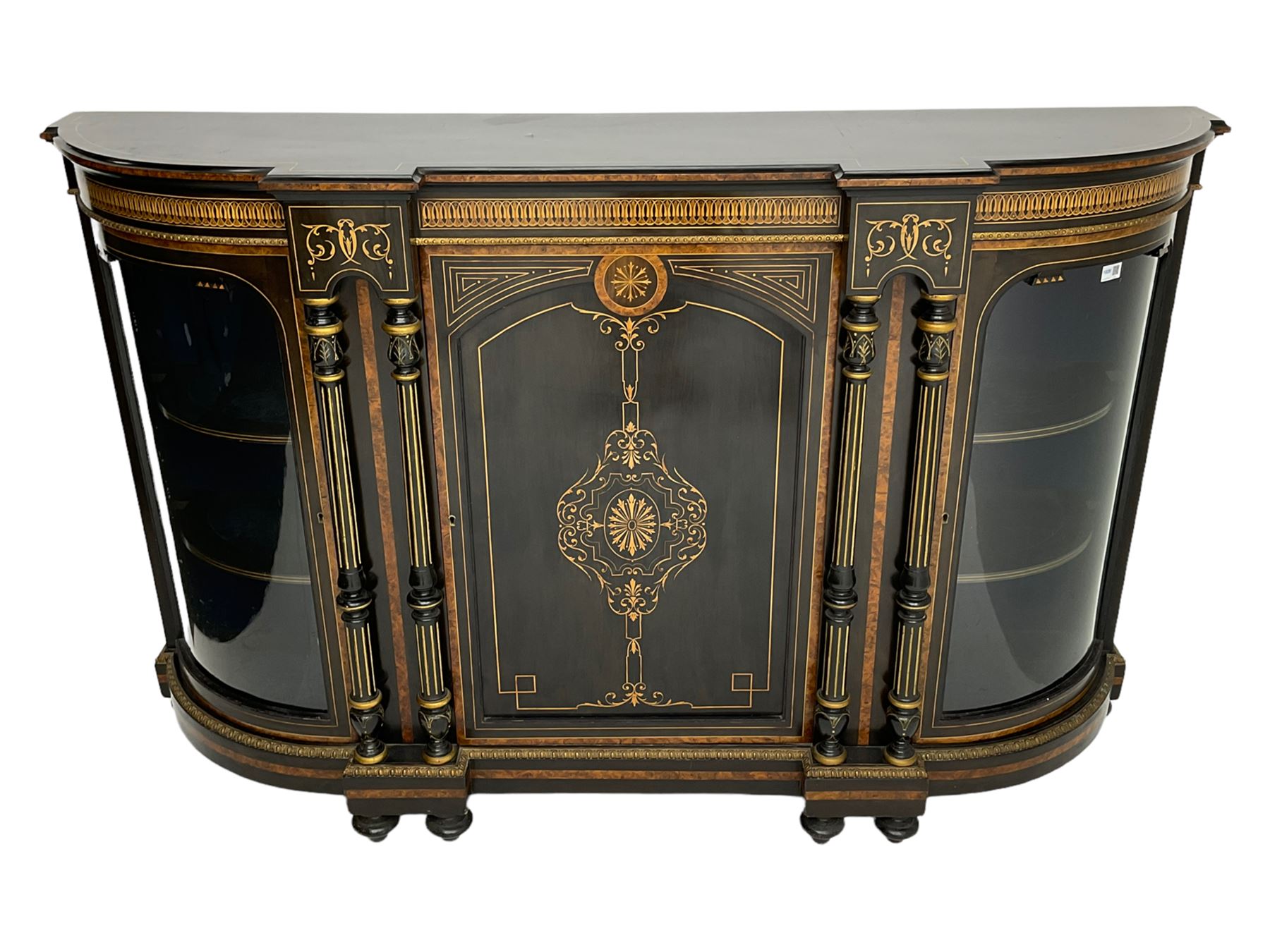 Victorian ebonised and inlaid credenza, break-front with curved ends, the front fitted with two curved glazed doors and central panelled door, inlaid with scrolling foliate and star motifs, quadruple turned and fluted pilasters to front, gilt egg and dart moulded edge on plinth base with figured walnut band, on turned feet