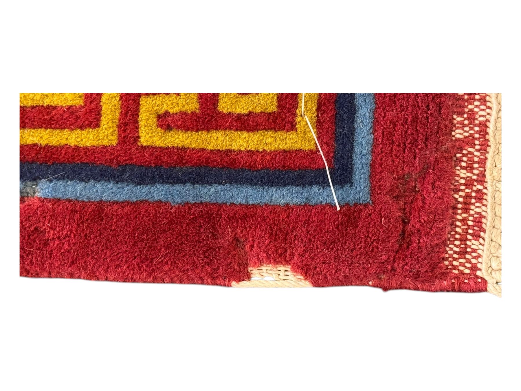 Tibetan-design handwoven rug, deep red field with three central medallions in yellow and blue, traditional yellow key border, white fringes on both ends