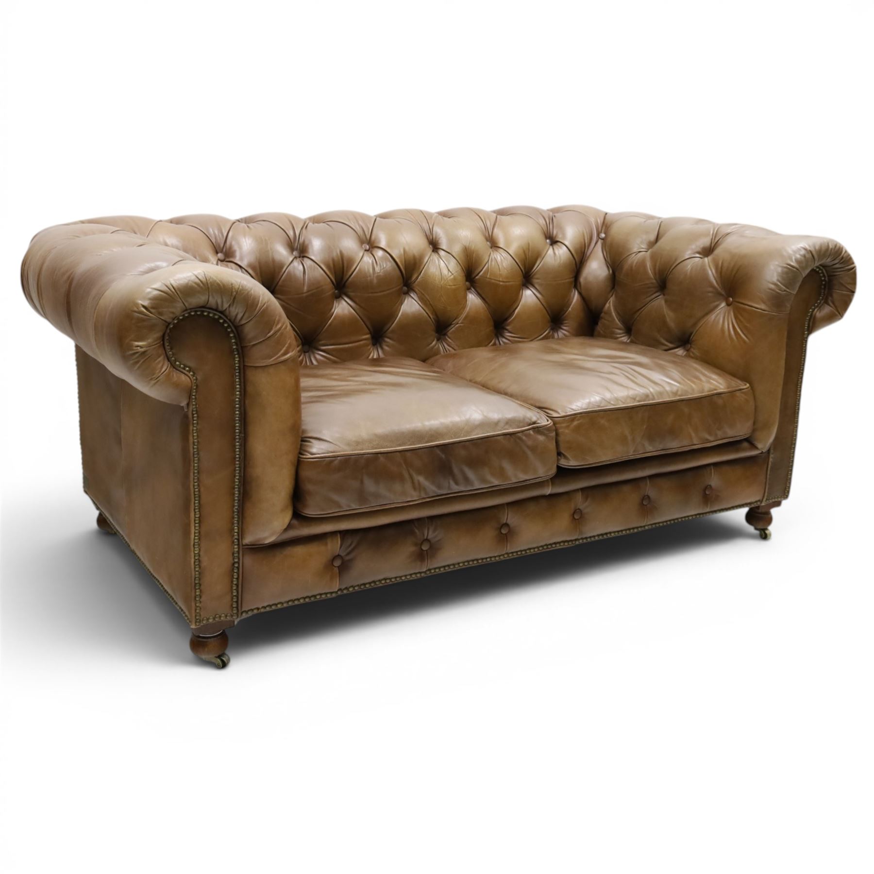 Timothy Oulton for HALO - Two seater brown leather chesterfield sofa, with button back and arms, with two loose cushions, raised on a dark stained supports terminating in castors 