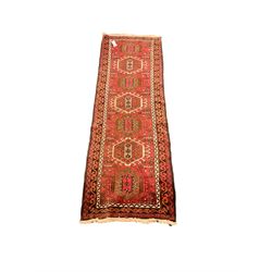 Persian red ground runner, the field decorated with seven stylised medallions, triple band border