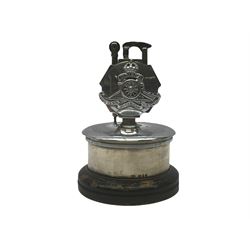 Royal Artillery presentation chromed metal table lighter, circular stand with silver band hallmarked London 1956 and ebonised base, H16cm