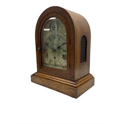 A large mid-20th century eight-day German mantle clock chiming the quarters and sounding the hours on five gong rods, in an arch topped oak case with a corresponding glazed door on a moulded plinth, sound frets to the sides and rear door, with a silvered etched dial plate and subsidiary chime/silent dial, engraved Roman numerals and minute track with steel spade hands.
With key and pendulum.

