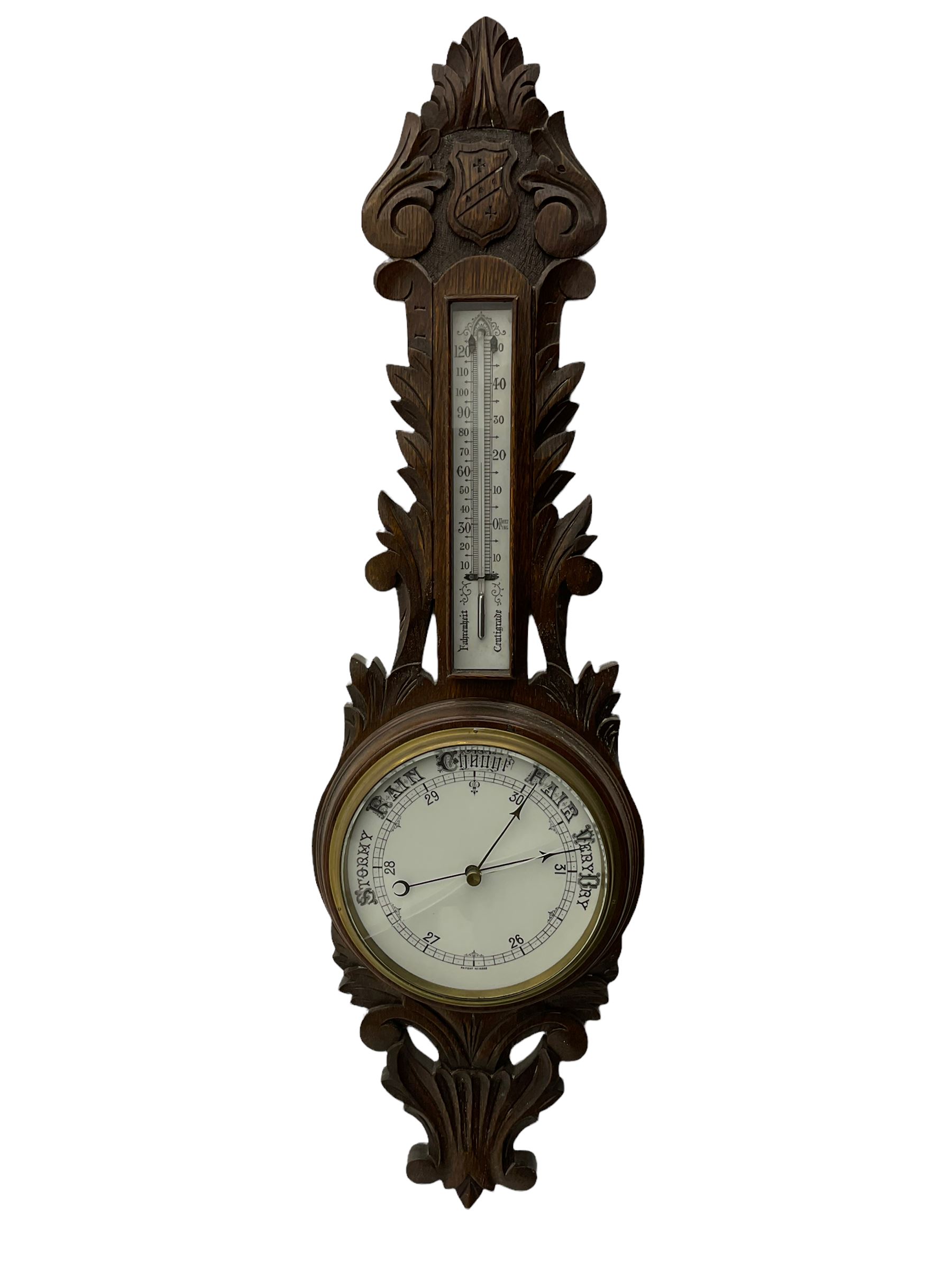 A 1920s oak cased patented aneroid barometer with openwork decorative carving, 8” enamel dial recording air pressure from 26 to 32 inches with weather predictions in gothic script, steel indicating hand and brass recording hand within a brass bezel and flat glass (glass cracked), with a boxed mercury thermometer recording the temperature in degrees centigrade and Fahrenheit.    

