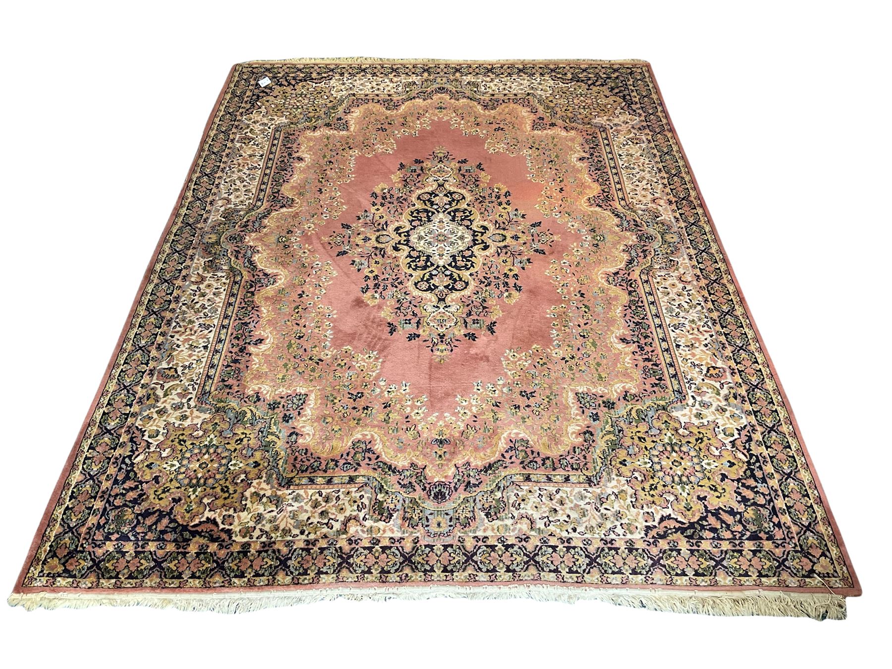 Large Persian design peach ground carpet, the field decorated with floral medallion, multi-band border decorated with repeating flower head pattern