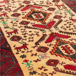 North East Persian Meshed Baluch rug, the ivory field decorated with two stepped diamond medallions and angular red motifs, interspersed with stylised horned animals, birds, flowerheads and geometric devices, enclosed by a dark brown border of repeating red serrated leaves and narrow ivory guard bands
