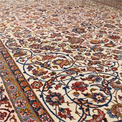 Central Persian Najafabad hand-knotted carpet, ivory field with an all-over scrolling floral design of palmettes, rosettes, and leafy vine work, enclosed by a wide floral main border flanked by multiple guard borders in madder red, indigo blue, green, and pale ochre, with cotton fringe ends 