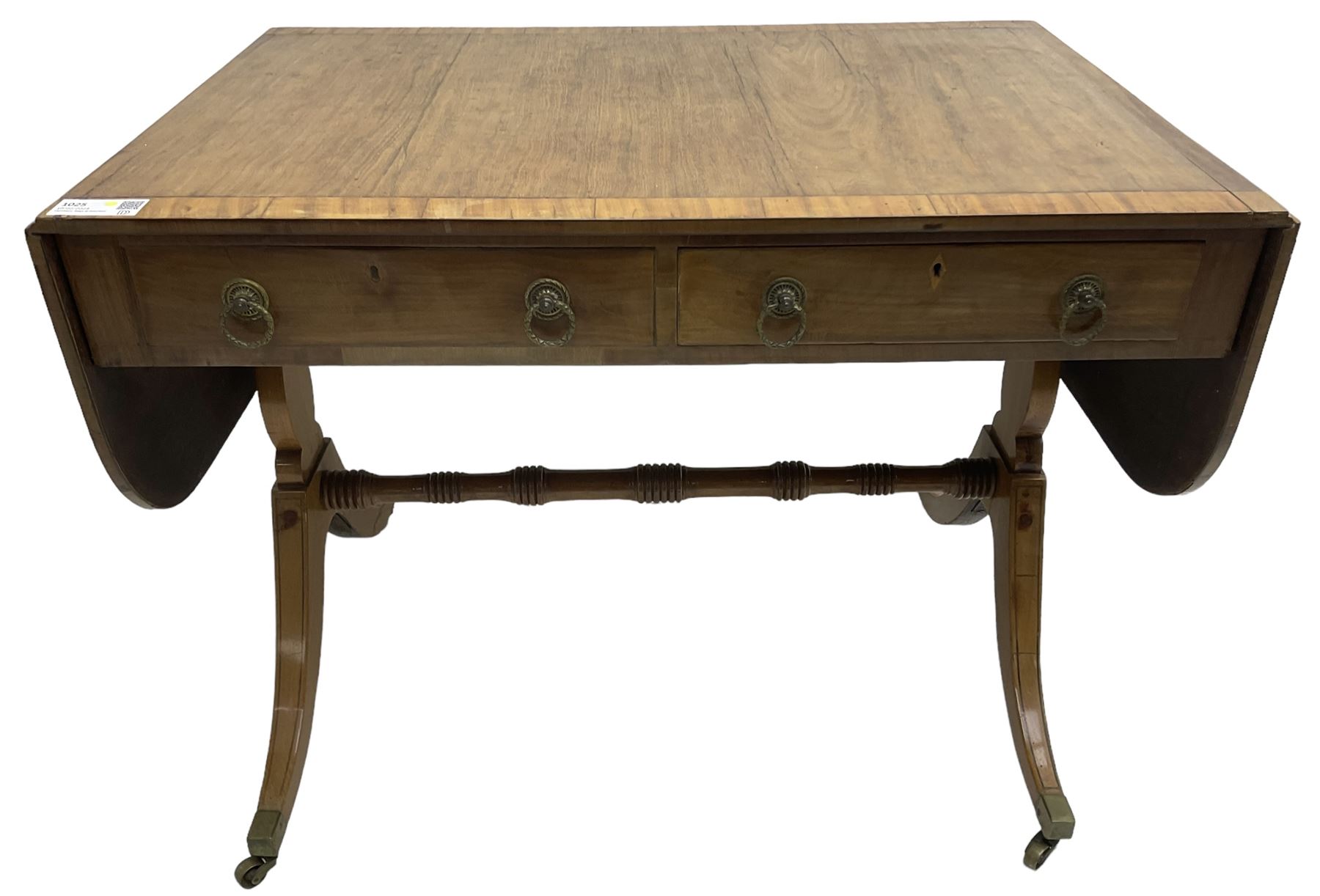 Regency mahogany sofa table, rectangular crossbanded top with twin drop-leaf ends, fitted with single drawer and one faux drawer, raised on shaped end supports united by ring turned stretcher