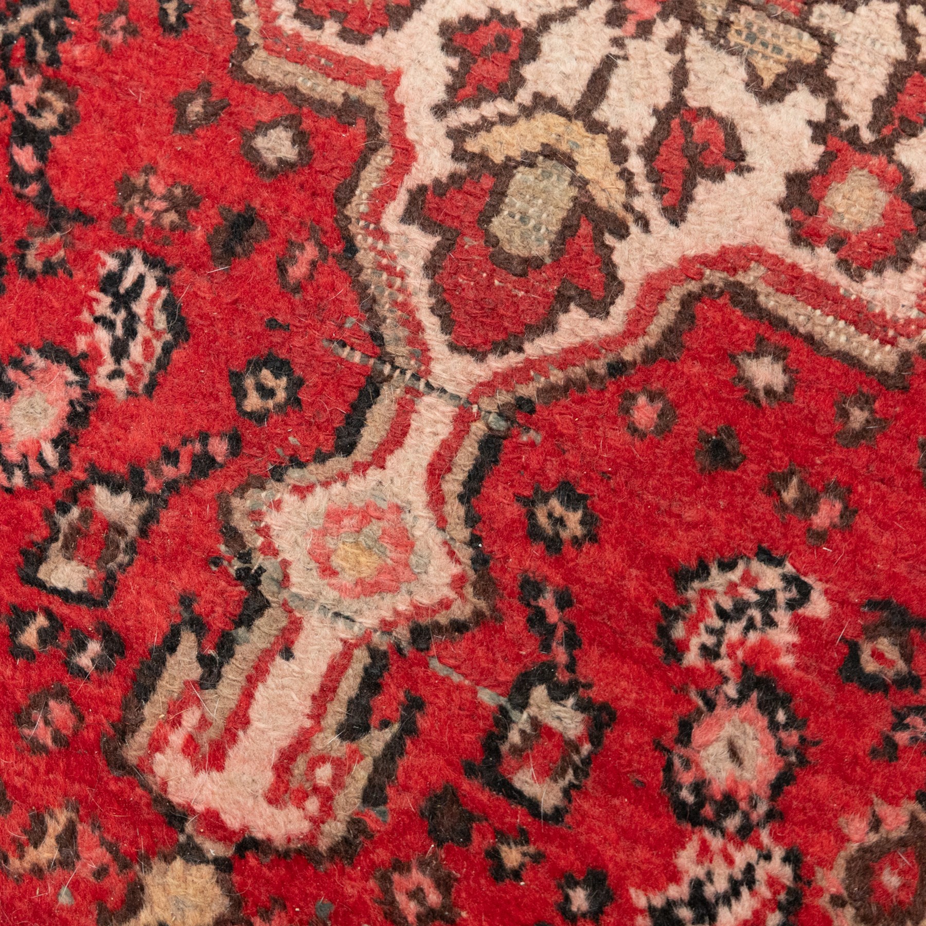 Persian crimson ground runner rug, the field decorated with repeating Herati motifs around an ivory pendant medallion, stepped ivory spandrels with stylised floral ornament, enclosed by a dark ground star border and narrow guard stripes