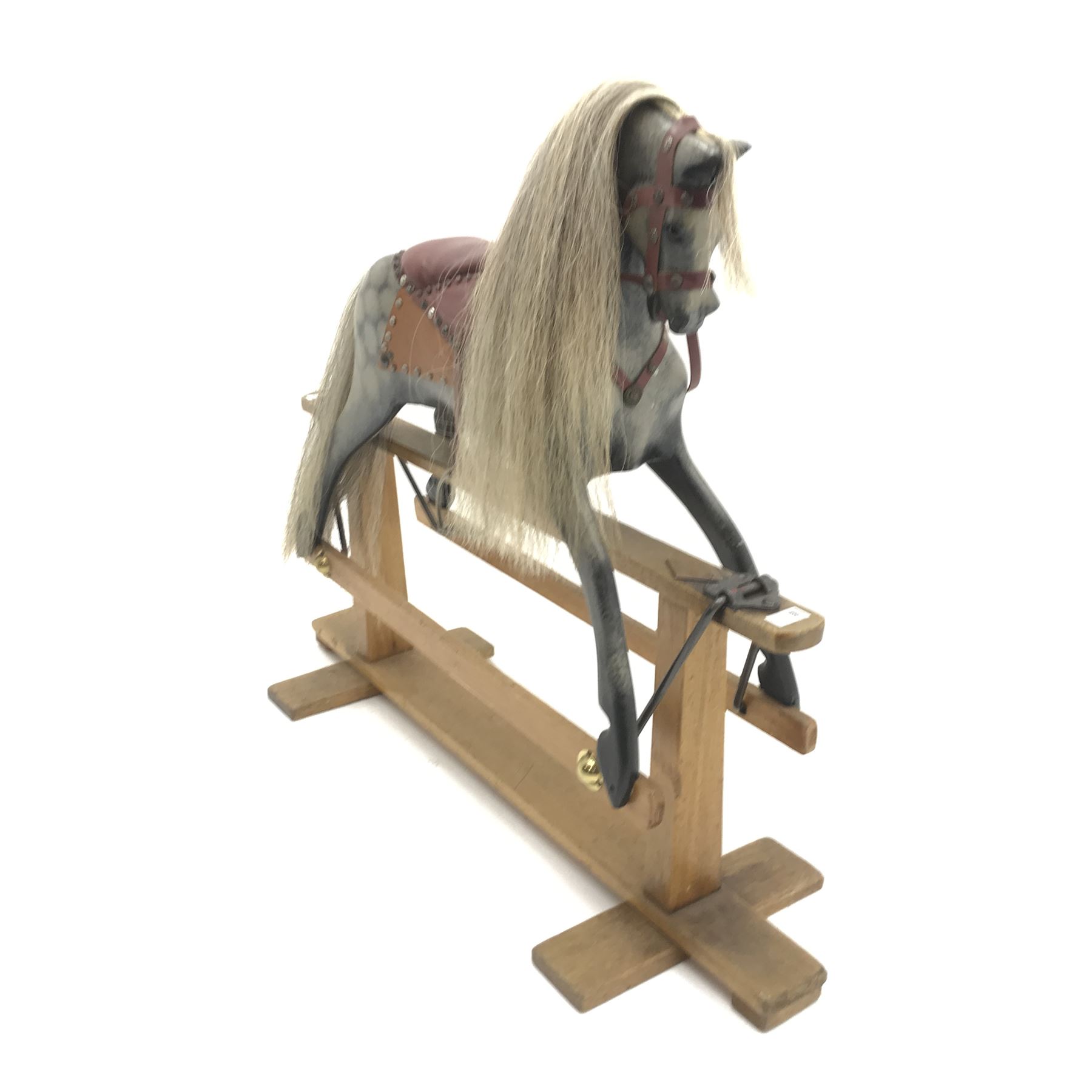 Early 20th century dapple grey rocking horse, leather rein and saddle with stirrups on trestle base