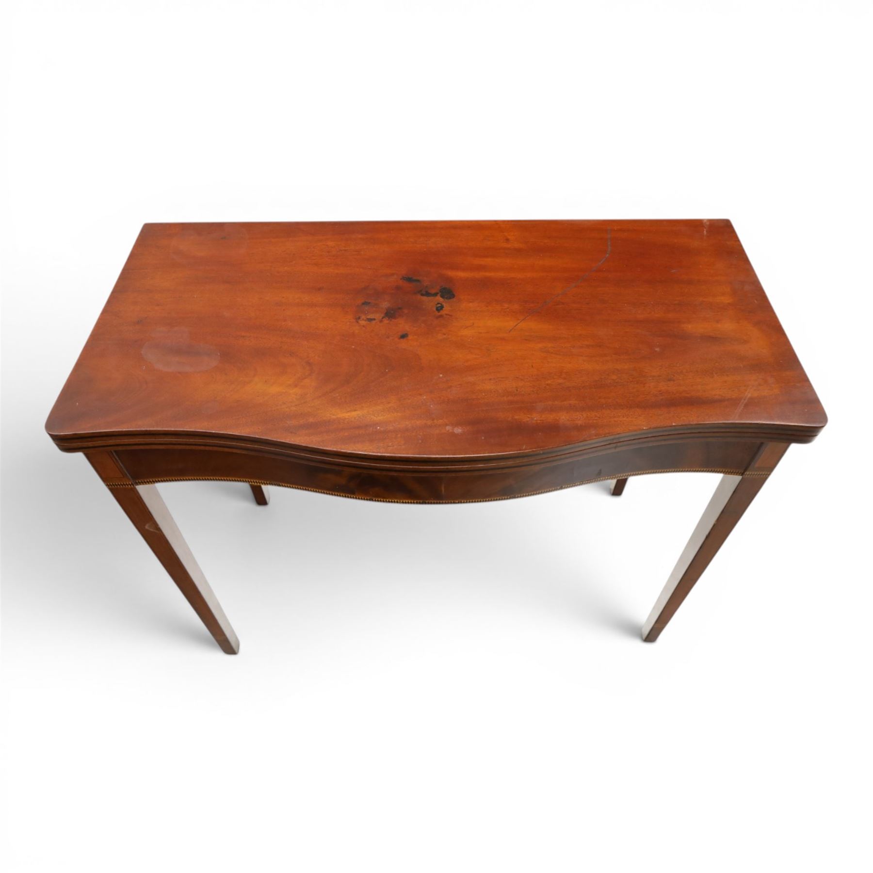 Regency period inlaid mahogany serpentine-fronted fold-over tea table, the shaped rectangular top with ebony-strung edge over a banded frieze with repeating lozenge inlaid banding, on square tapering supports