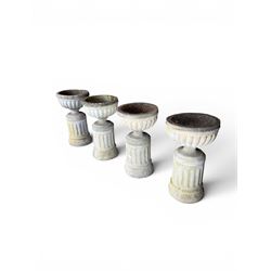 Four 20th century good quality weathered cast stone pedestal urns, circular lobed bowls with rope twist and lattice border, raised on squat base with fluted columns