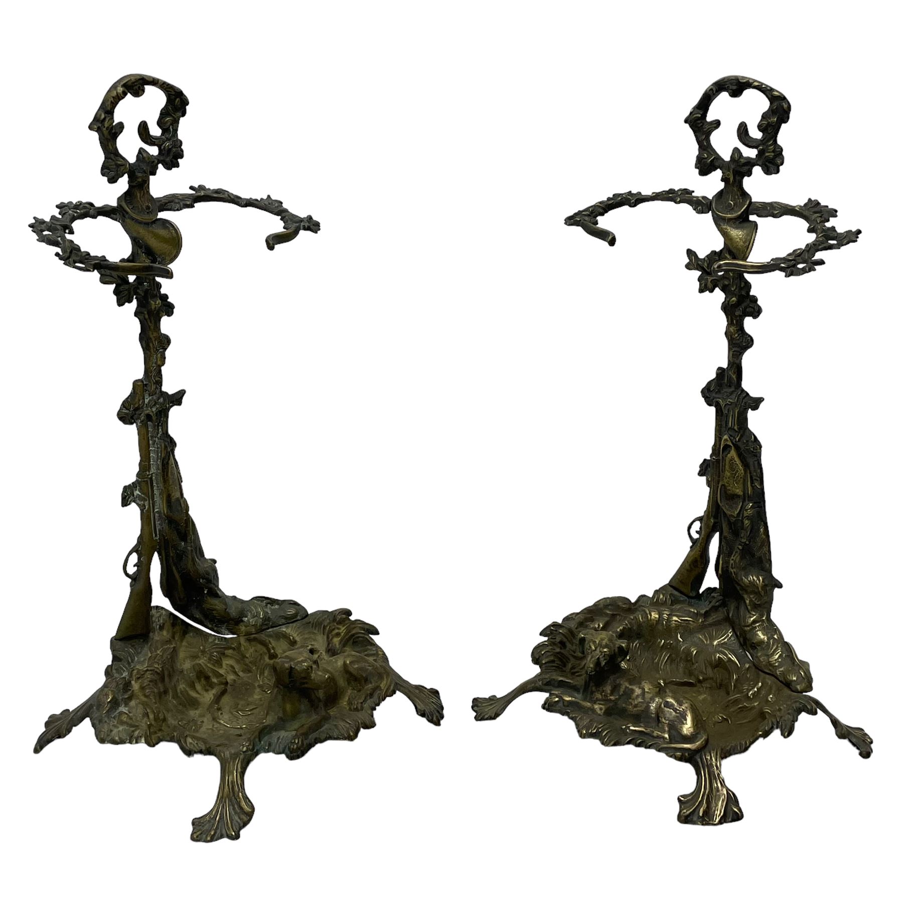 Pair of cast brass hallway umbrella or stick stands, in the form of a tree decorated with trailing flowering foliage branches, the stem with hunting horn over leaning shotgun, shaped naturalist tray base with hunting hound and out splayed foliate cast feet 